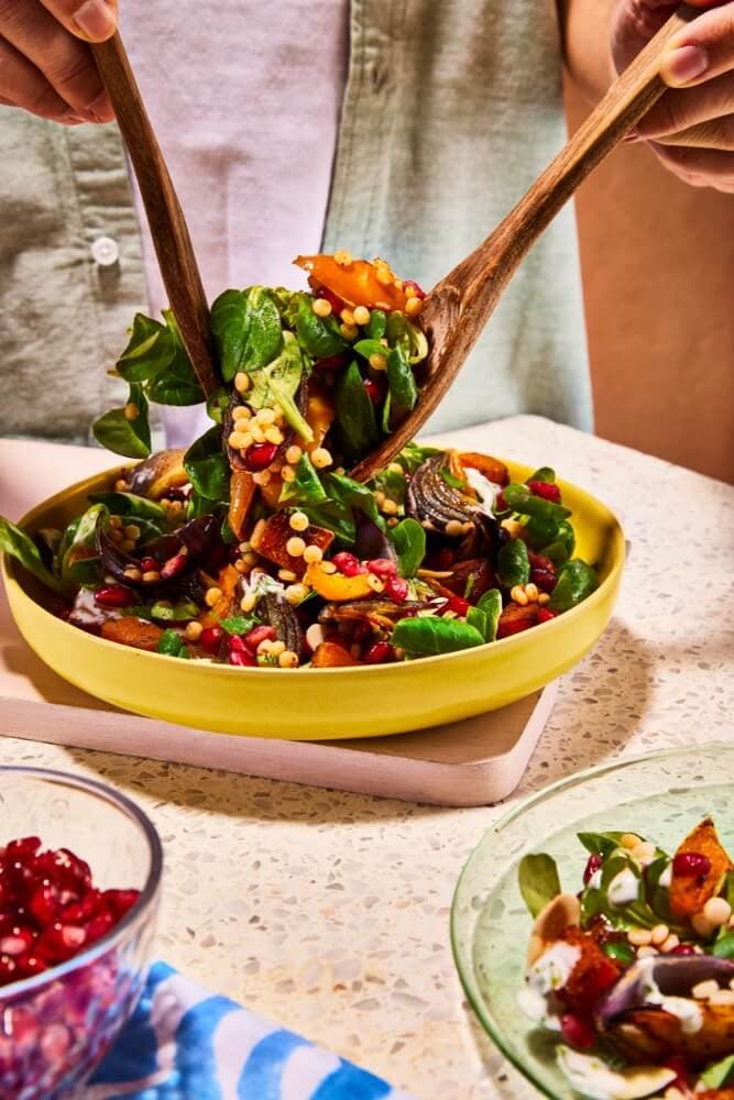 A colourful grain and leaf salad being served from a bowl